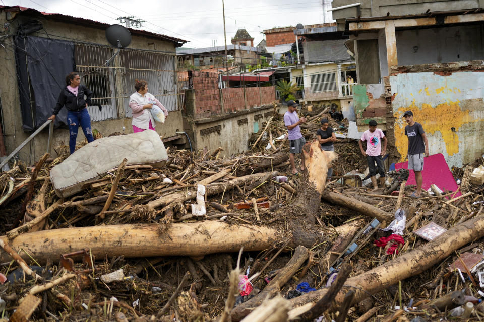 Residents walk through the debris left by flooding caused by a river that overflowed after days of intense rain in Las Tejerias, Venezuela, Sunday, Oct. 9, 2022. (AP Photo/Matias Delacroix)