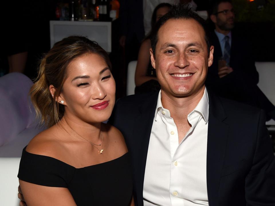 Jenna Ushkowitz and David Stanley sitting on a white couch at a gala in October 2019.