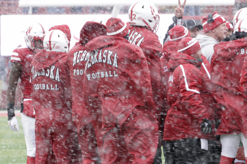 FILE - Nebraska players bundle up against the cold and snow during a time out in the second half of an NCAA college football game against Michigan State in Lincoln, Neb., Saturday, Nov. 17, 2018. The Big Ten's longstanding policy to generally not play November night games outdoors after daylight savings ends has been eliminated with the start of the conference's new television contract this season. (AP Photo/Nati Harnik, File)