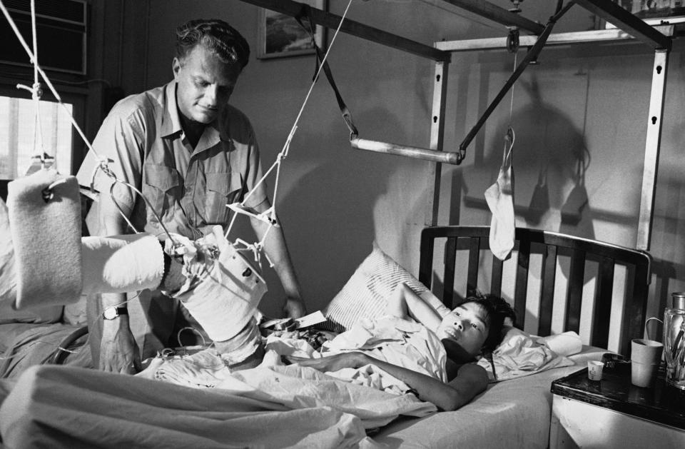 <p>Evangelist Billy Graham visits a Viet Cong prisoner-of-war in traction and being treated for battle wounds at the U.S. Third Field Hospital in Saigon on Dec. 21, 1966. Graham had shortly before addressed a large gathering at Saigon’s U.S. Airbase. (Photo: Henry Huet/AP) </p>