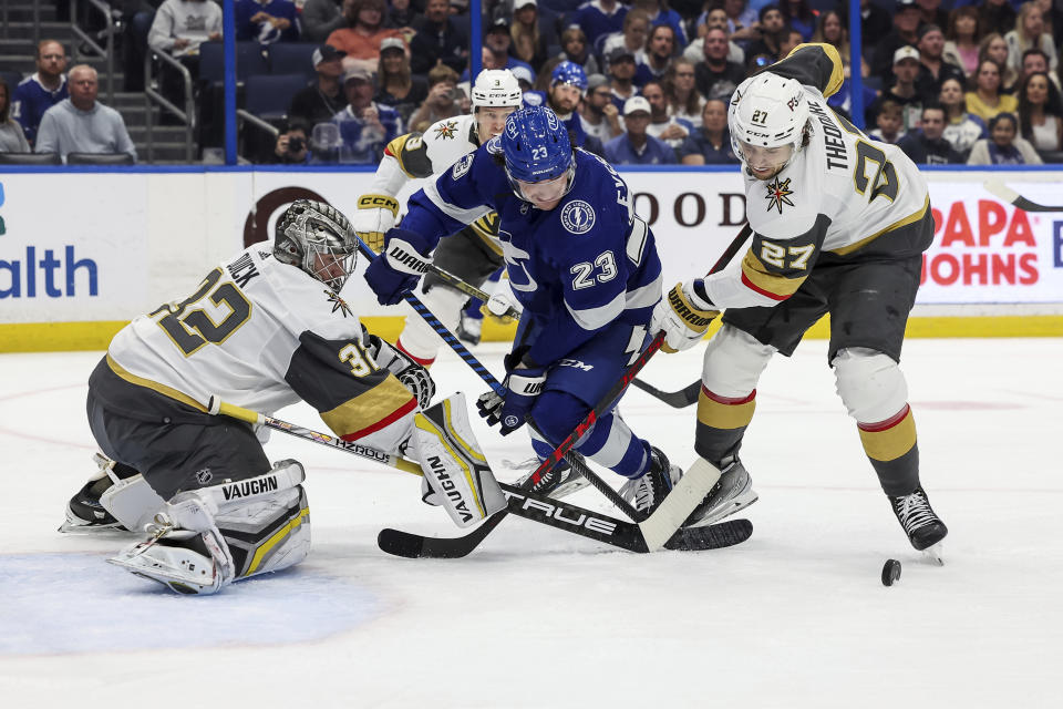 Vegas Golden Knights' Shea Theodore (27) checks Tampa Bay Lightning's Michael Eyssimont (23) in front of goaltender Jonathan Quick during the second period of an NHL hockey game Thursday, March 9, 2023, in Tampa, Fla. (AP Photo/Mike Carlson)