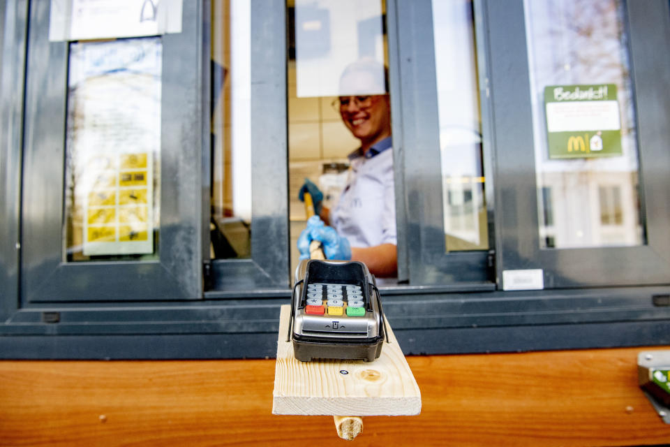 APERLDOORN, NETHERLANDS - 2020/03/27: A McDonald's restaurant worker seen passing a payment card machine using a self made contact free extension device in order to keep the 1.5 meters recommended social distance with the drive through customer. Due to the COVID-19 coronavirus outbreak, Mcdonald's restaurants in the Netherlands has recommended it's staffs to keep a recommended social distance of 1.5 meter from its customers. Drive through restaurants are only accepting wireless card payments and food has to be left on a pick up counter for the customers collect after staff members has left the area in order to minimize the chances of the virus from spreading. (Photo by Robin Utrecht/SOPA Images/LightRocket via Getty Images)