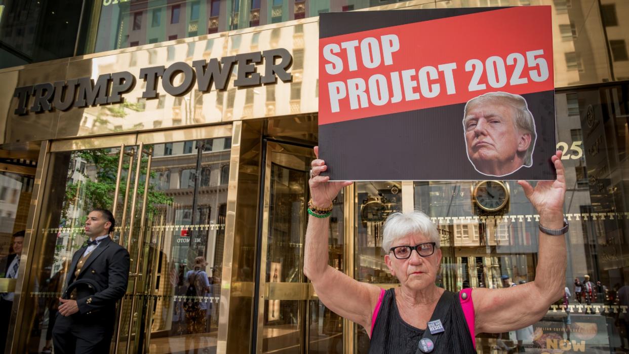  A protestor holding a banner reading No Dictators In The USA outside Trump Tower. 