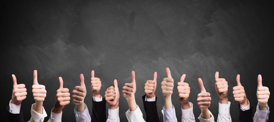 many thumbs up in business sleeves in front of a blackboard