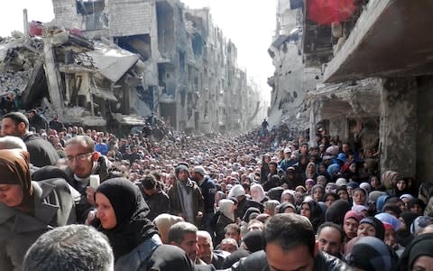 Residents wait in line to receive food aid distributed in the Yarmouk refugee camp on January 31, 2014 in Damascus, Syria.  - Credit: UNRWA