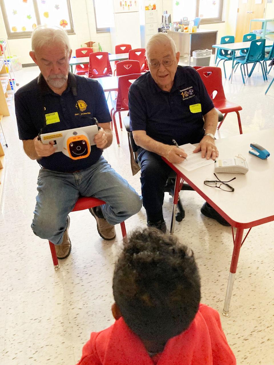 Lions Club Members Ron Wilson and Gaylan Good screen a student’s eyes with a non-invasive camera. Students in the Oak Ridge Schools were screened after parents signed them up.