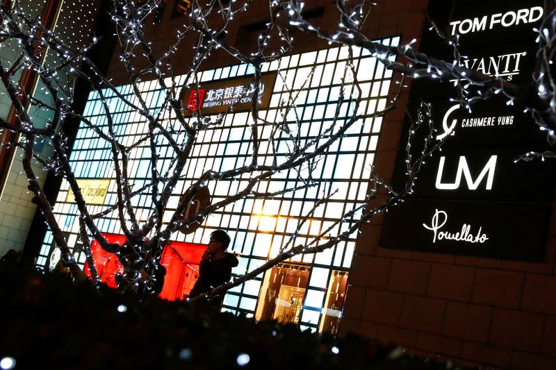 FILE PHOTO: FILE PHOTO: A man walks outside a department store selling luxury brands in Beijing