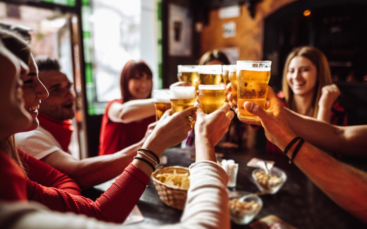 friends drinking beer at a bar - Getty Images