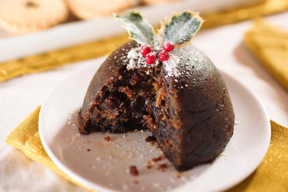 christmas pudding with slice removed in nice, bright directional lighting yum mince pies are in the background to fill a hole if needed