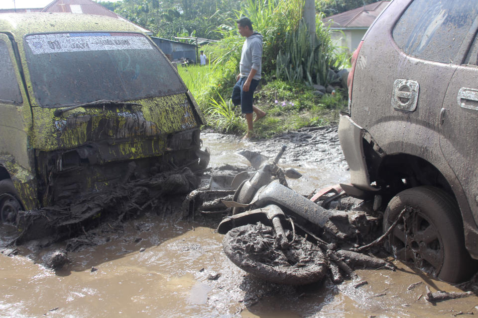 A man walks past the wreckages of cars and a motorcycle swept away by a flash flood in Agam, West Sumatra, Indonesia, Sunday, May 12, 2024. Heavy rains and torrents of cold lava and mud rushing down a volcano on Indonesia’s Sumatra island have triggered flash floods that killed more than a dozen of people and injured several others, officials said Sunday. (AP Photo/Ali Nayaka)