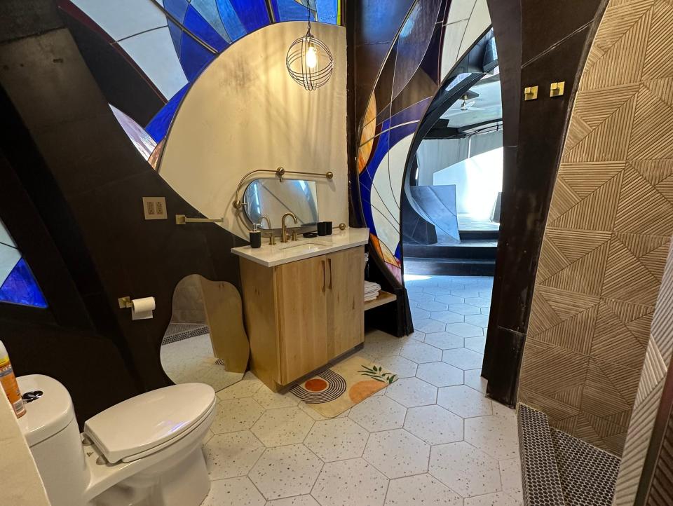Bathroom area with a small vanity and a large blue stained-glass wall