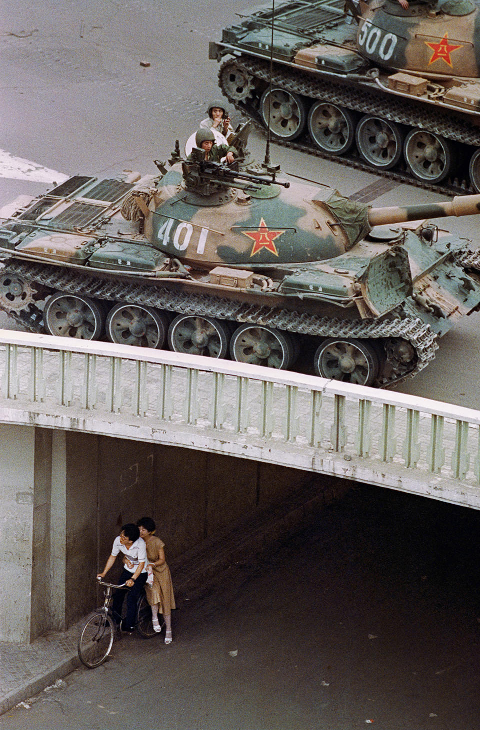 A young couple on a bicycle hide from Chinese soldiers in a tank overhead during the Tiananmen Square protests that were crushed June 4, 1989. | Liu Heung Shing