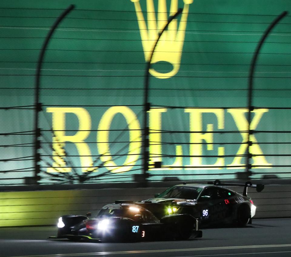 In this 2023 file photo, racers run past the backstretch banners in the early morning hours during the Rolex 24 at Daytona International Speedway.