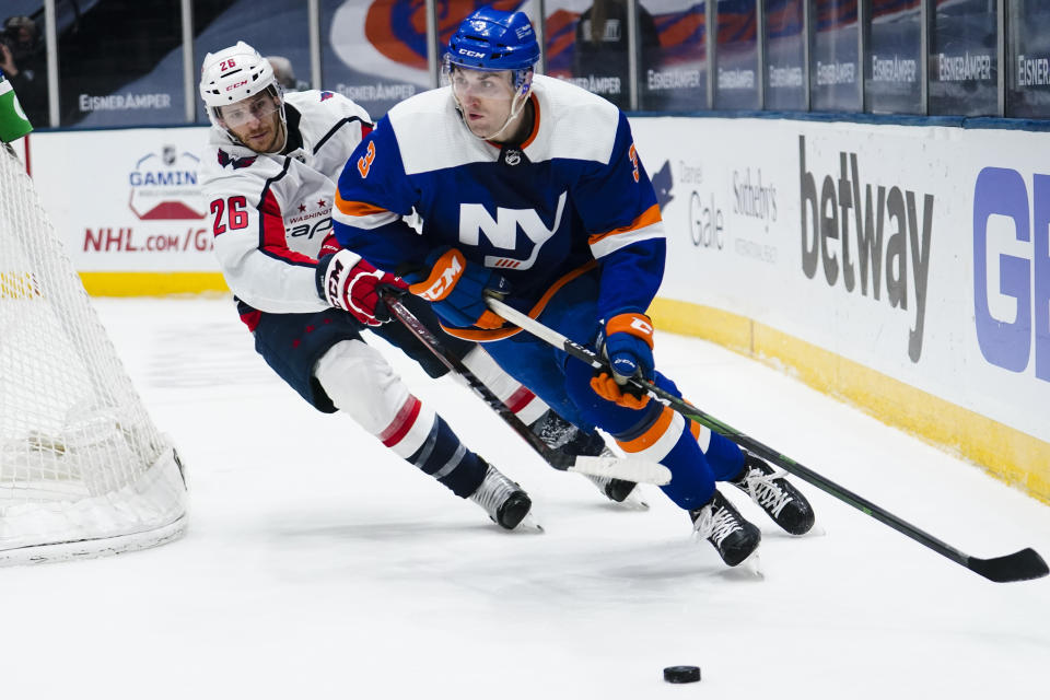 Washington Capitals' Nic Dowd (26) fights for control of the puck with New York Islanders' Adam Pelech (3) during the third period of an NHL hockey game Saturday, April 24, 2021, in Uniondale, N.Y. The Capitals won 6-3. (AP Photo/Frank Franklin II)