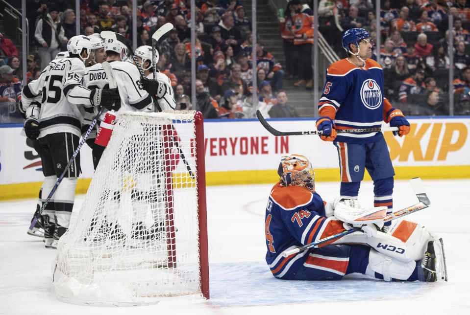 Los Angles Kings, left, celebrate after a goal against Edmonton Oilers goalie Stuart Skinner (74) as Oilers' Cody Ceci (5) looks on during first-period NHL hockey game action in Edmonton, Alberta, Monday, Feb. 26, 2024. (Jason Franson/The Canadian Press via AP)