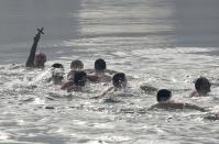 Bulgarian Vyacheslav Borisov, 29, holds a wooden cross as he swims in the waters of a lake on Epiphany Day in Sofia January 6, 2014. Orthodox priests throughout the country bless the waters by throwing a cross into it as worshippers try to retrieve the cross. It is strongly believed that catching the cross brings health and prosperity to the person who catches it. REUTERS/Stoyan Nenov (BULGARIA - Tags: SOCIETY RELIGION)