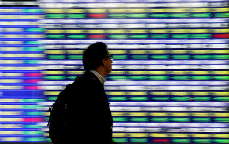 A man walks past an electronic stock quotation board outside a brokerage in Tokyo, Japan, November 13, 2018. REUTERS/Toru Hanai/Files