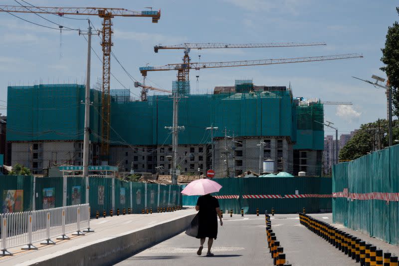 FILE PHOTO: A woman walks near a construction site of apartment buildings in Beijing