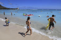 Beach goers take to the waves on Waikiki Beach, Thursday, June, 23, 2022 in Honolulu. In a major expansion of gun rights after a series of mass shootings, the Supreme Court said Thursday that Americans have a right to carry firearms in public for self-defense.