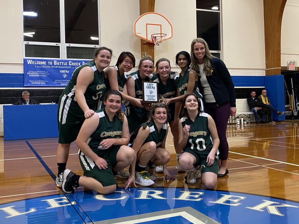 Will Carleton head coach Lakyn Sattison and the girls varsity basketball team hold their Lady Tigers tournament championship trophy.