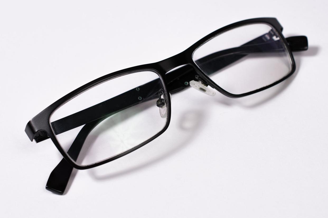 Pair of folded black glasses on white background