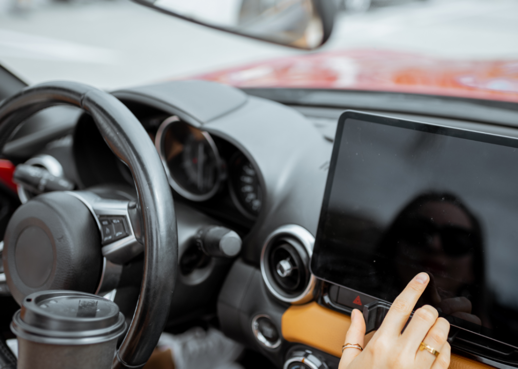 hand touching dark touchscreen on car dashboard