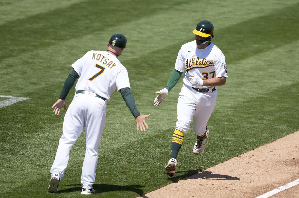 Oakland Athletics' Aramis Garcia (37) is congratulated by third base coach Mark Kotsay (7) as he rounds the bases after hitting a two-run home run against the Detroit Tigers during the second inning of a baseball game on Saturday, April 17, 2021, in Oakland, Calif. (AP Photo/Tony Avelar)