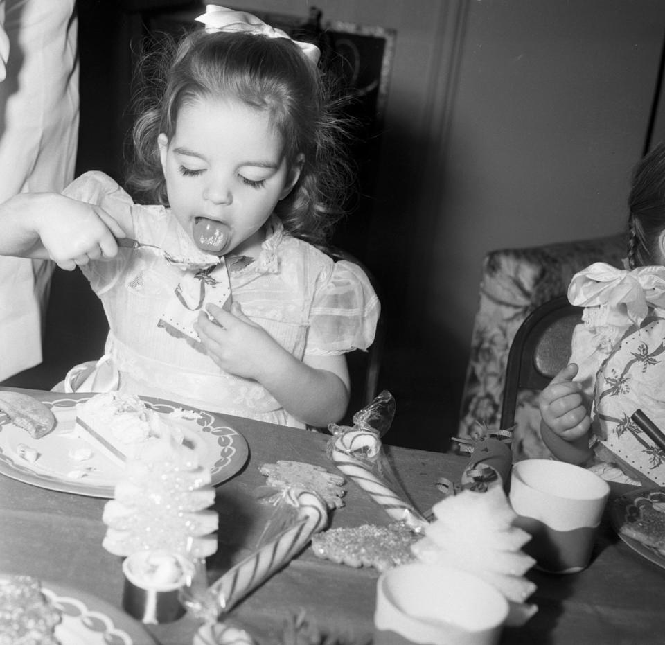 <p>A young Liza Minnelli helps herself to some christmas treats at a children's party in 1948. Minnelli, the daughter of Judy Garland, wears her holiday best by way of a white pinafore dress and matching bow. </p>