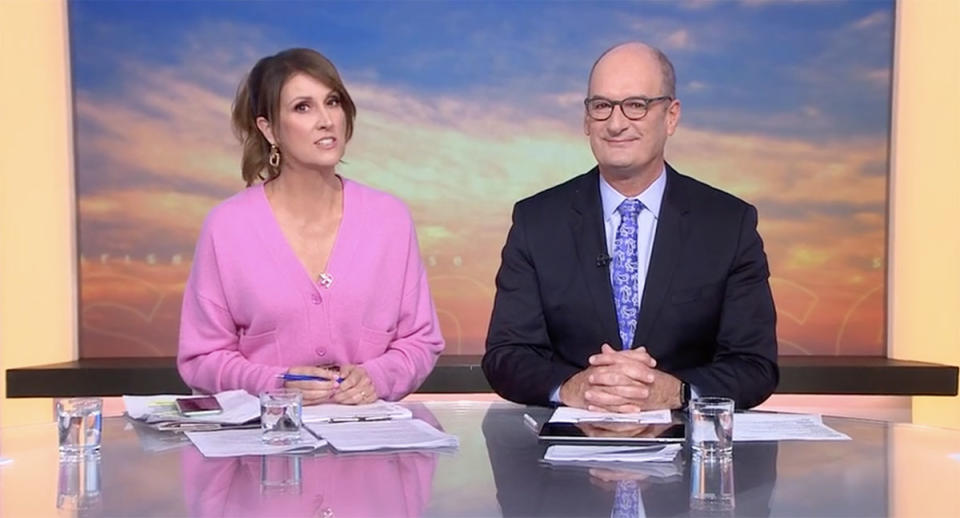 Natalie Barr and David 'Kochie' Koch present the morning news on Sunrise. Natalie Barr is wearing a pink cardigan and her hair is tied up.