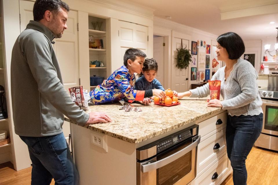 Jen Robinson, right, and her husband, Jonathan, watch as their kids, Ethan and Madison, assemble the Tray of Togetherness, filling it with oranges and sweets, on Thursday, January 19, 2023, inside their Plumstead home to usher in good luck for the Lunar New Year.