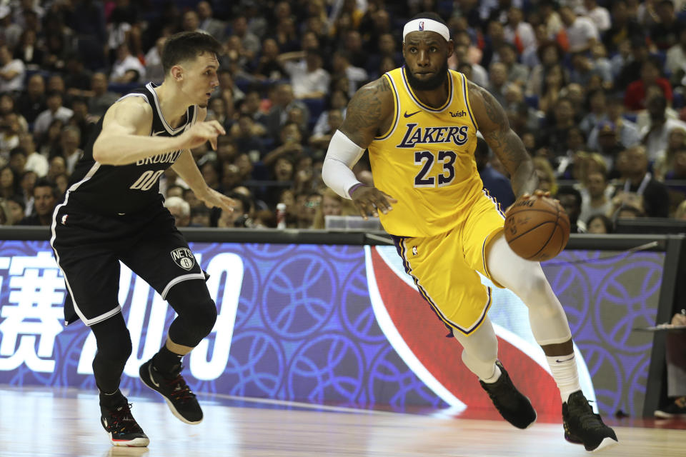 Los Angeles Lakers' Lebron James, right, drives against Brooklyn Nets' Rodions Kurucs, left, during their preseason NBA game in Shanghai, China, Thursday, Oct. 10, 2019. In response to the NBA defending Daryl Morey's freedom of speech, Chinese officials took it away from the Los Angeles Lakers and Brooklyn Nets, with the usual media sessions canceled in Shanghai, including a scheduled news conference from NBA Commissioner Adam Silver and postgame news conferences with the teams. (AP Photo) /// DQo=