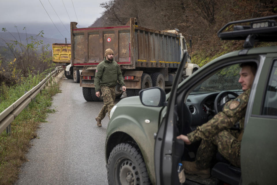 Latvian soldiers part of the NATO-led peackeeping mission in Kosovo patrol near heavy vehicles parked by local Serbs blocking the road near the village of Uglare, in northern Kosovo on Monday, Dec. 12, 2022. Barricades erected by local Serbs in the north of Kosovo remained up on Monday for the third consecutive day, despite calls from the international community to be removed and the situation de-escalated. Kosovo on Saturday postponed a local election due Dec. 18 in four municipalities with a predominantly ethnic Serb population, in an effort to defuse recent tensions there that have also caused relations with neighboring Serbia to deteriorate further. (AP Photo/Visar Kryeziu)