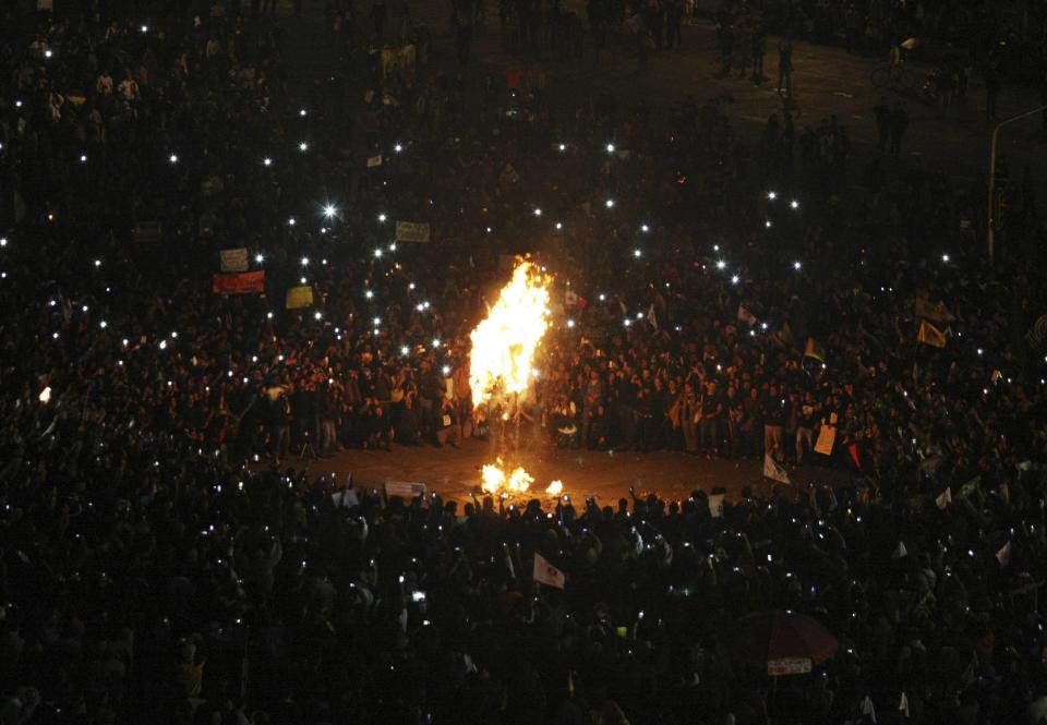 Demonstrators look at a burning effigy of President Enrique Pena Nieto during a protest in support of 43 missing Ayotzinapa students in Mexico City