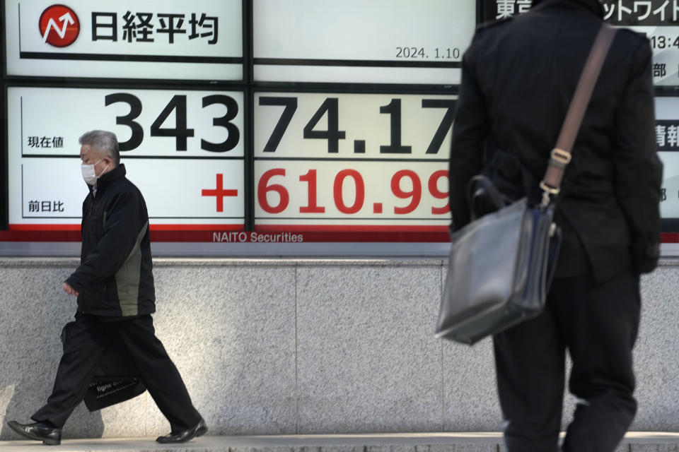 People walk past an electronic stock board showing Japan's Nikkei 225 index at a securities firm Wednesday, Jan. 10, 2024 in Tokyo. (AP Photo/Shuji Kajiyama)