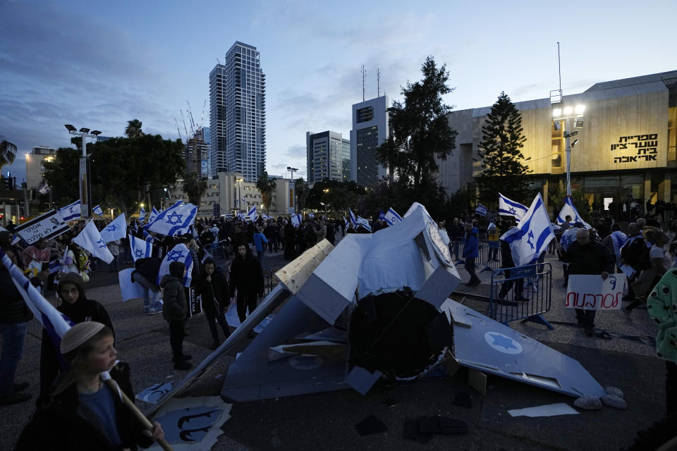 An installation representing a crashed Israeli Air Force fighter jet placed previously by anti-government activists lies run rail after an attack by right-wing Israelis a rally in support of Prime Minister Benjamin Netanyahu's government plans to overhaul the judicial system, in Tel Aviv, Israel, Thursday, March 30, 2023. (AP Photo/Ariel Schalit)