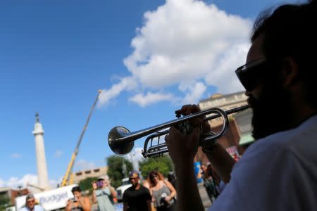 A man plays a trumpet while construction crew prepare a monument of Robert E. Lee, who was a general in the Confederate Army, for removal in New Orleans, Louisiana, U.S., May 19, 2017. REUTERS/Jonathan Bachman