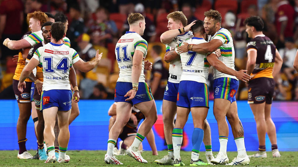 Canberra Raiders players celebrate on field after defeating the Brisbane Broncos.