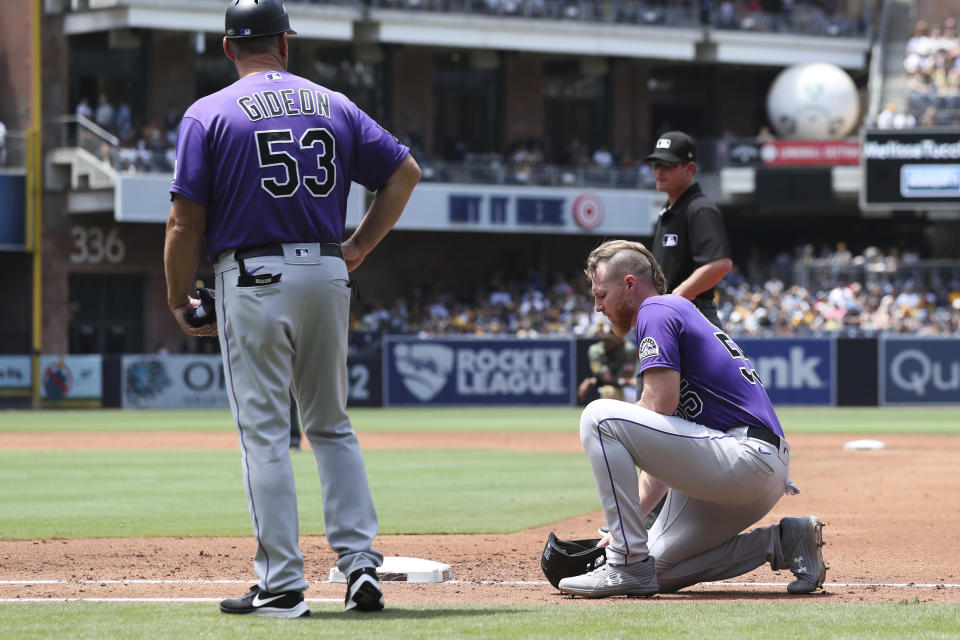 Colorado Rockies' Jon Gray, right, kneels at first base after a collision with San Diego Padres starting pitcher Ryan Weathers as Ronnie Gideon looks on in the third inning of a baseball game Sunday, July 11, 2021, in San Diego. (AP Photo/Derrick Tuskan)