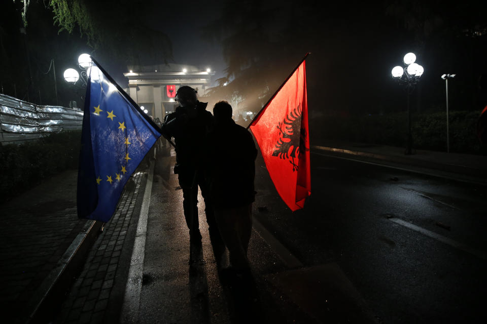 A protester holding EU and Albanian flags is blocked by a police officer guarding the parliament during an anti-government rally in Tirana, Albania, Saturday, April 13, 2019. Albanian opposition parties have gathered supporters calling for the government's resignation and an early parliamentary election. (AP Photo/Visar Kryeziu)