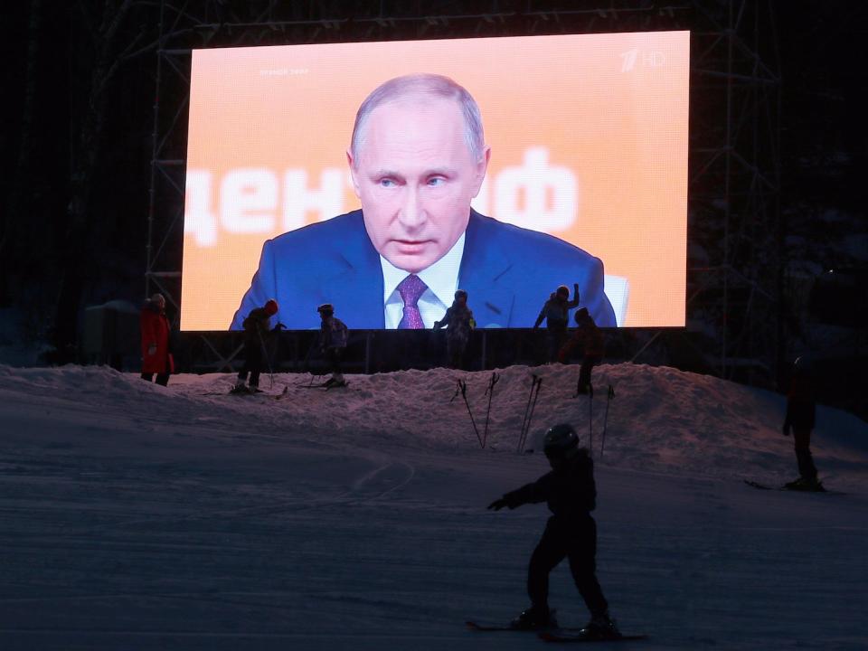 Visitors gather near an open-air monitor during a live broadcast, showing Russian President Vladimir Putin's annual end-of-year news conference, at the Bobrovy Log ski resort in the Siberian city of Krasnoyarsk, Russia, December 14, 2017.