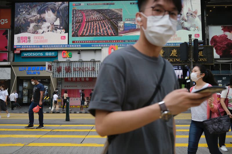 People walk past a TV screen showing news over Beijing's approves Hong Kong security bill, in Hong Kong