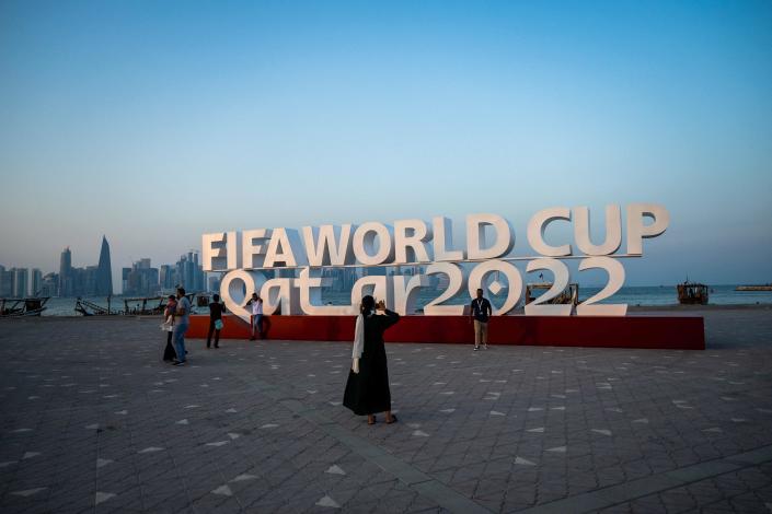 Visitors take photos with a FIFA World Cup sign in Doha on October 23, 2022, ahead of the Qatar 2022 FIFA World Cup football tournament. / Credit: JEWEL SAMAD/AFP via Getty Images