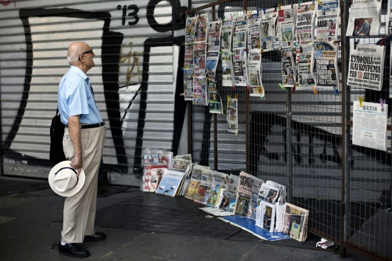 A man reads newspaper headlines at a kiosk in Athens, on July 11, 2015