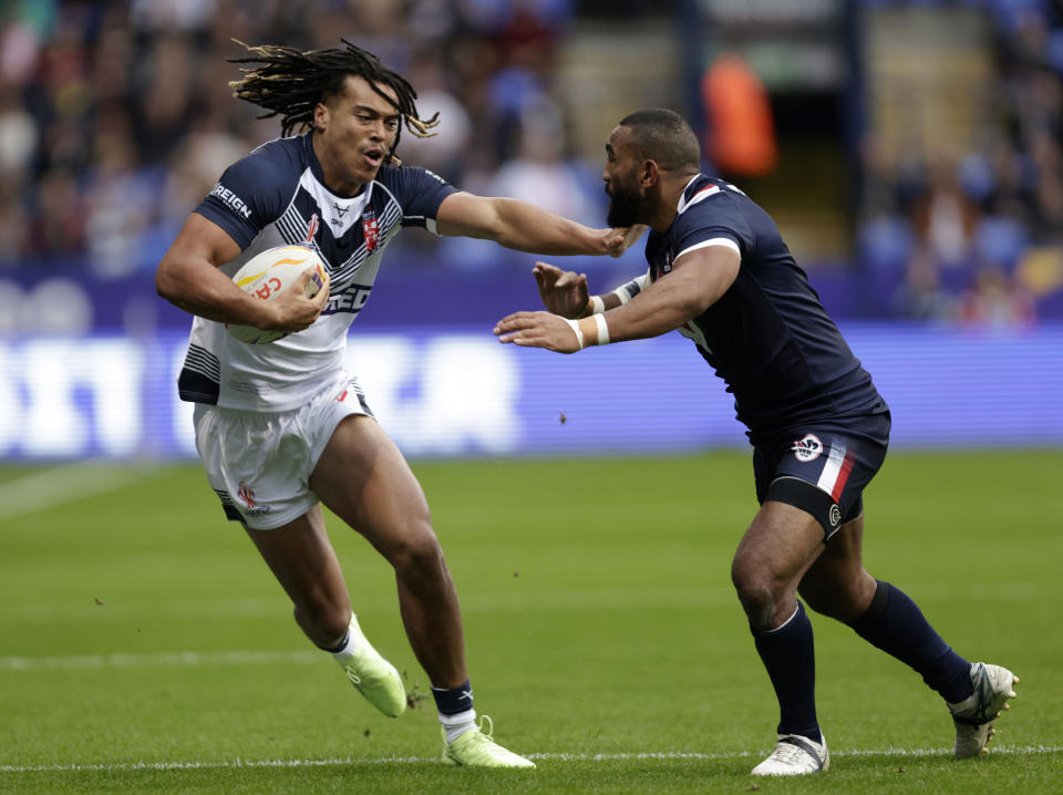 England's Dom Young, left, is tackled by France's Samisoni Langi during the Rugby League World Cup group A match between England and France at the University of Bolton Stadium, Bolton, England, Saturday Oct. 22, 2022. (Richard Sellers/PA via AP)