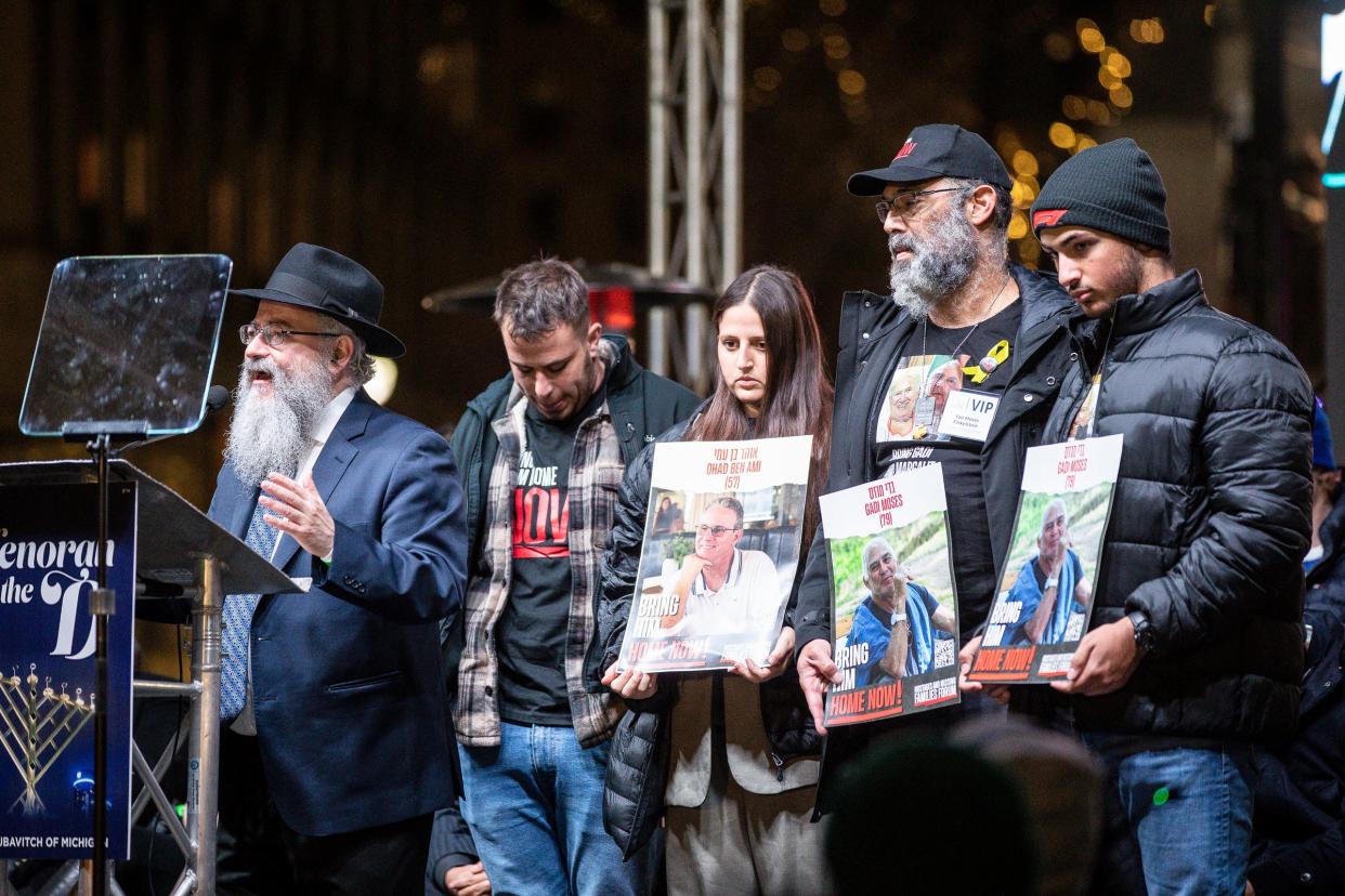 Rabbi Kasriel Shemtov, left, leads a prayer on stage for families still held hostage by Hamas during the annual Menorah in the D at Campus Martius in Detroit on Thursday, Dec. 7, 2023.