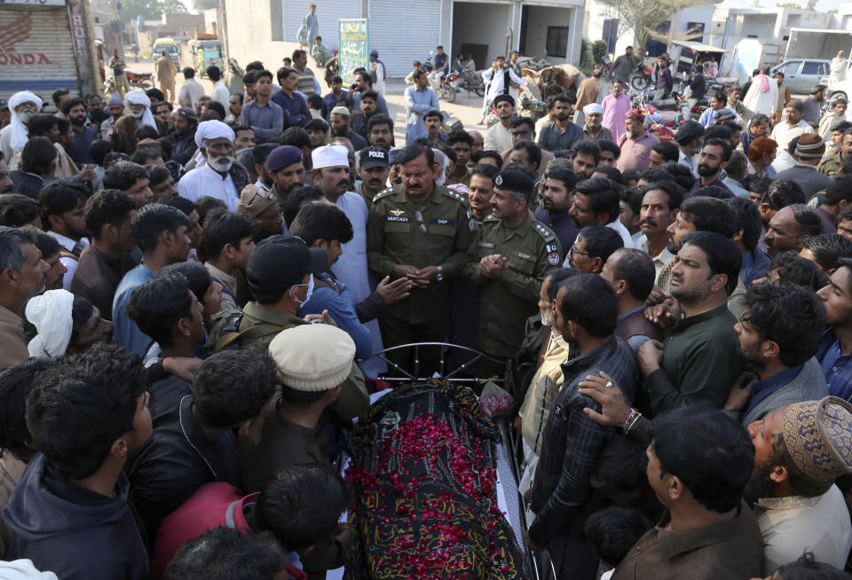 Police officers, relatives and villagers gather around the body of Mushtaq Ahmed, 41, who was killed when an enraged mob stoned him to death for allegedly desecrating the Quran, during his funeral in Tulamba, a remote village in the district of Khanewal in eastern Pakistan, Sunday, Feb. 13, 2022. Mob attacks on people accused of blasphemy are common in this conservative Islamic nation where blasphemy is punishable by death. (AP Photo/Asim Tanveer)