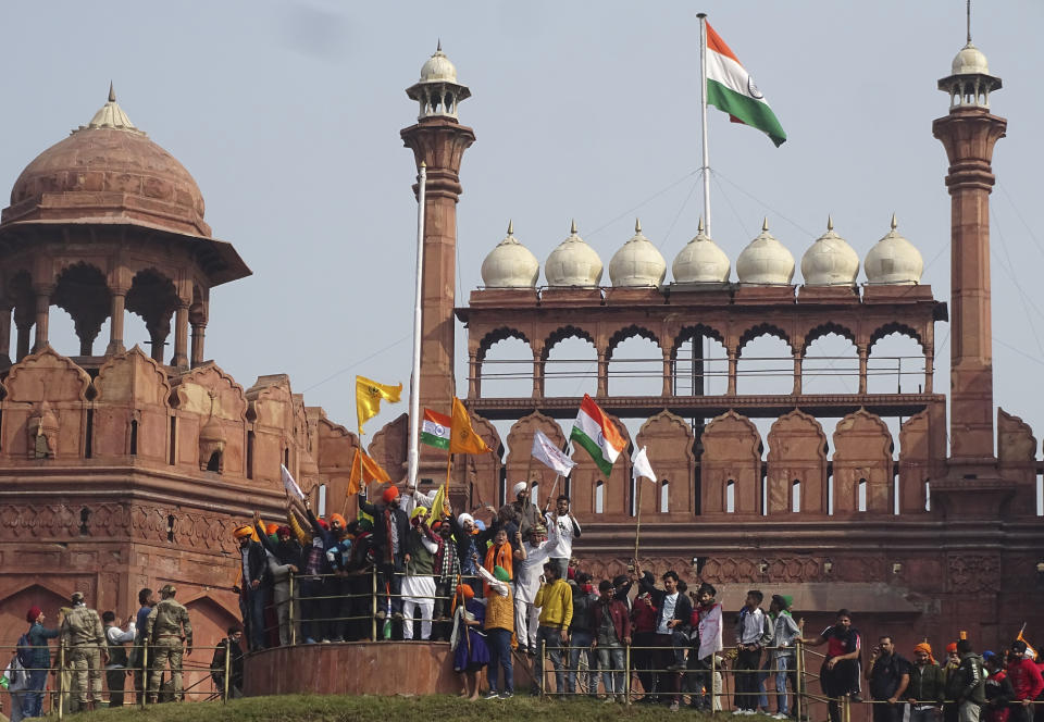 Indian farmers shout slogans from the rampart of the historic Red Fort monument in New Delhi, India, Tuesday, Jan. 26, 2021. Tens of thousands of protesting farmers drove long lines of tractors into India's capital on Tuesday, breaking through police barricades, defying tear gas and storming the historic Red Fort as the nation celebrated Republic Day. (AP Photo/Dinesh Joshi)