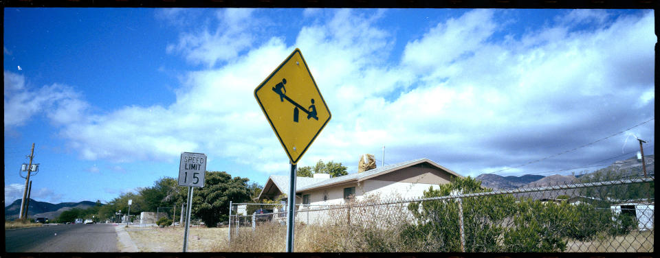 FILE - A "playground ahead" warning stands by the side of a road on the outskirts of Bisbee, Ariz., Oct. 26, 2021. Bisbee was home to Paul and Leizza Adams, and their six children, before Paul and Leizza were charged with child sexual abuse. (AP Photo/Dario Lopez-Mills)