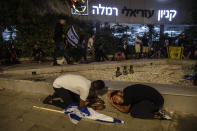 Jewish nationalist demonstrators take cover during a barrage of rockets fired from the Gaza Strip toward central Israel, in the Israeli town of Ramla, Tuesday, May 11, 2021. The protesters had gathered in an attempted show of strength in a predominantly Arab neighborhood. (AP Photo/Heidi Levine)