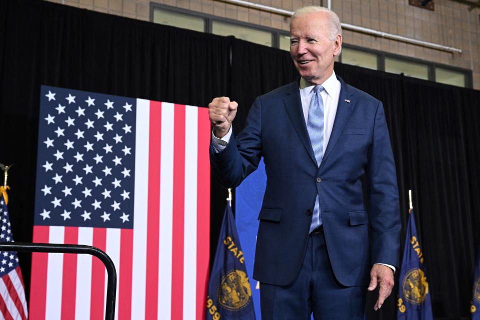 Joe Biden pumps his fist while standing in front of an American flag.